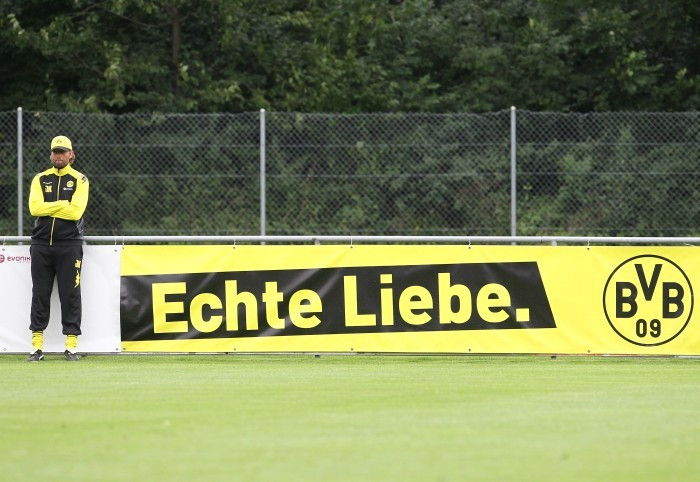 Jürgen Klopp steht auf dem Trainingsplatz vor einer "Echte Liebe"-Werbebande