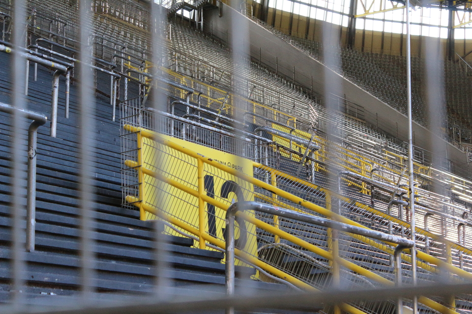 Man blickt durch den Zaun auf einen leeren Block 13 auf der Südtribüne.