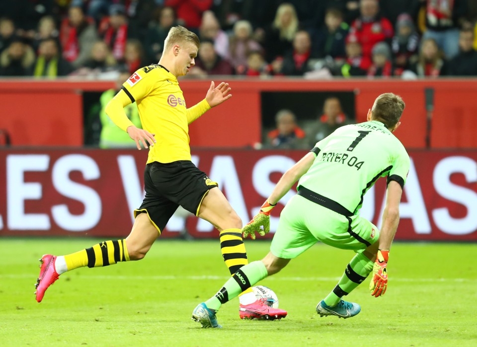 Haaland, mit Blick auf den Ball, dribbelt an Leverkusener Torhüter vorbei.